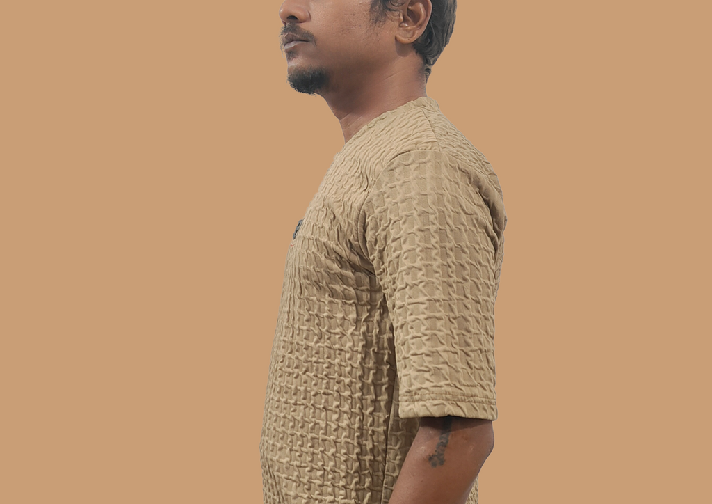 Man wearing a textured beige shirt against a brown background