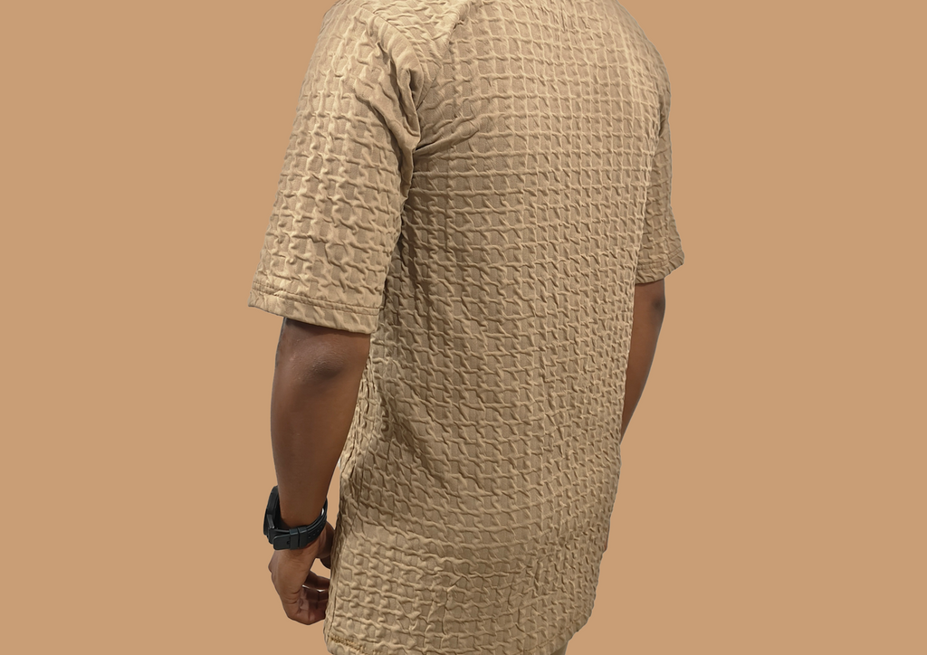 Person wearing a textured beige kurta against a brown background