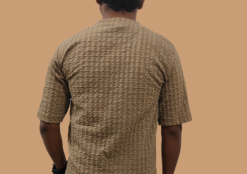 Man wearing a textured beige shirt against a brown background