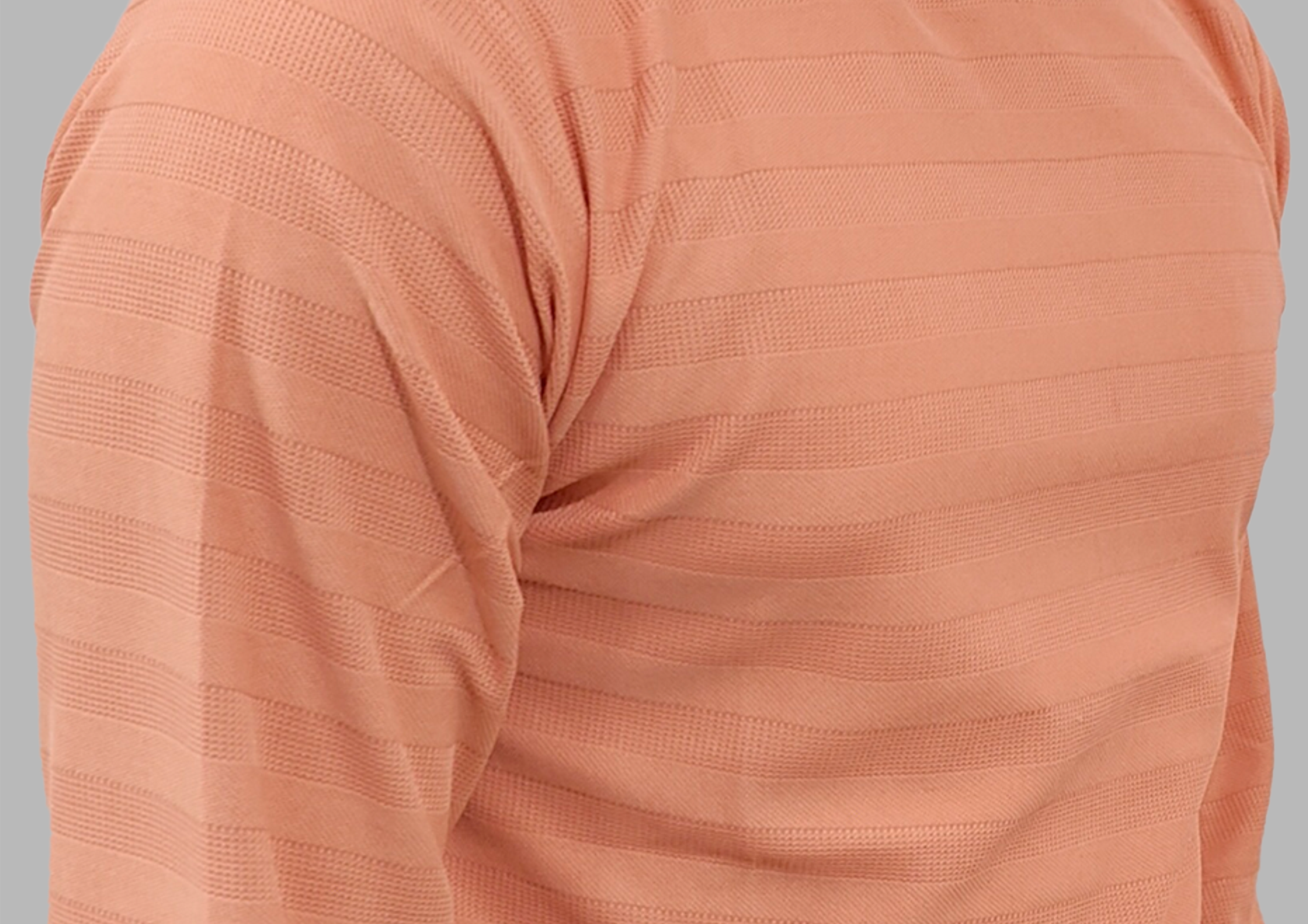 Close-up of a peach-colored textured fabric garment on a gray background