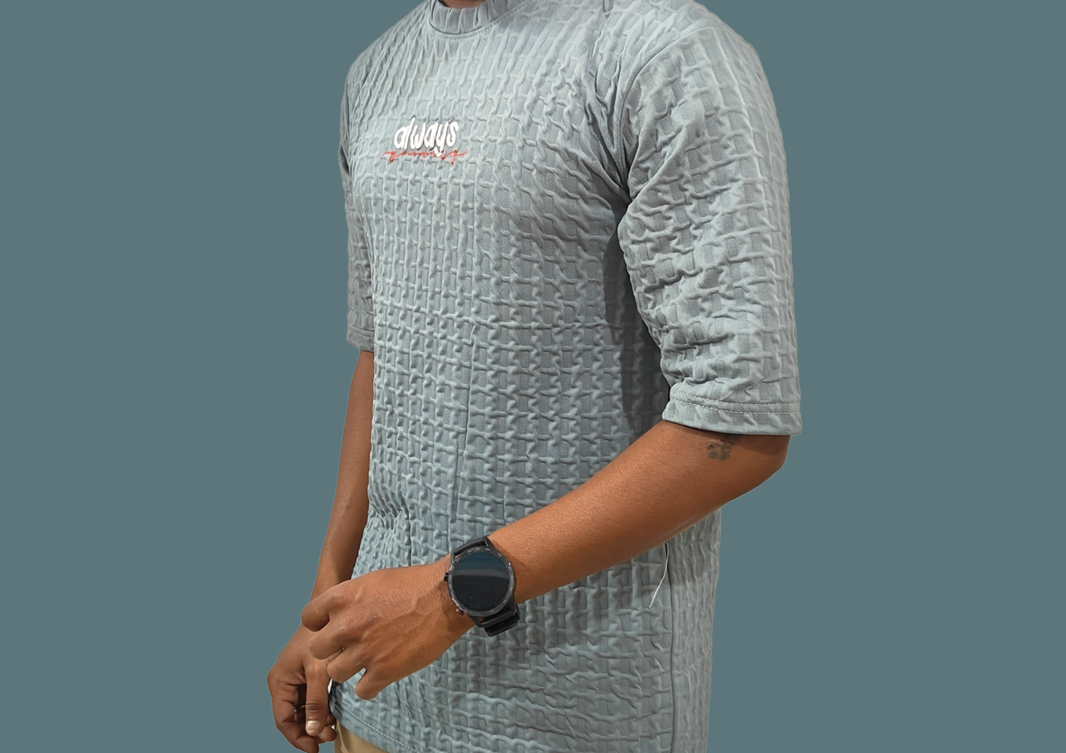 Person wearing a textured gray shirt with a visible brand logo on a plain background