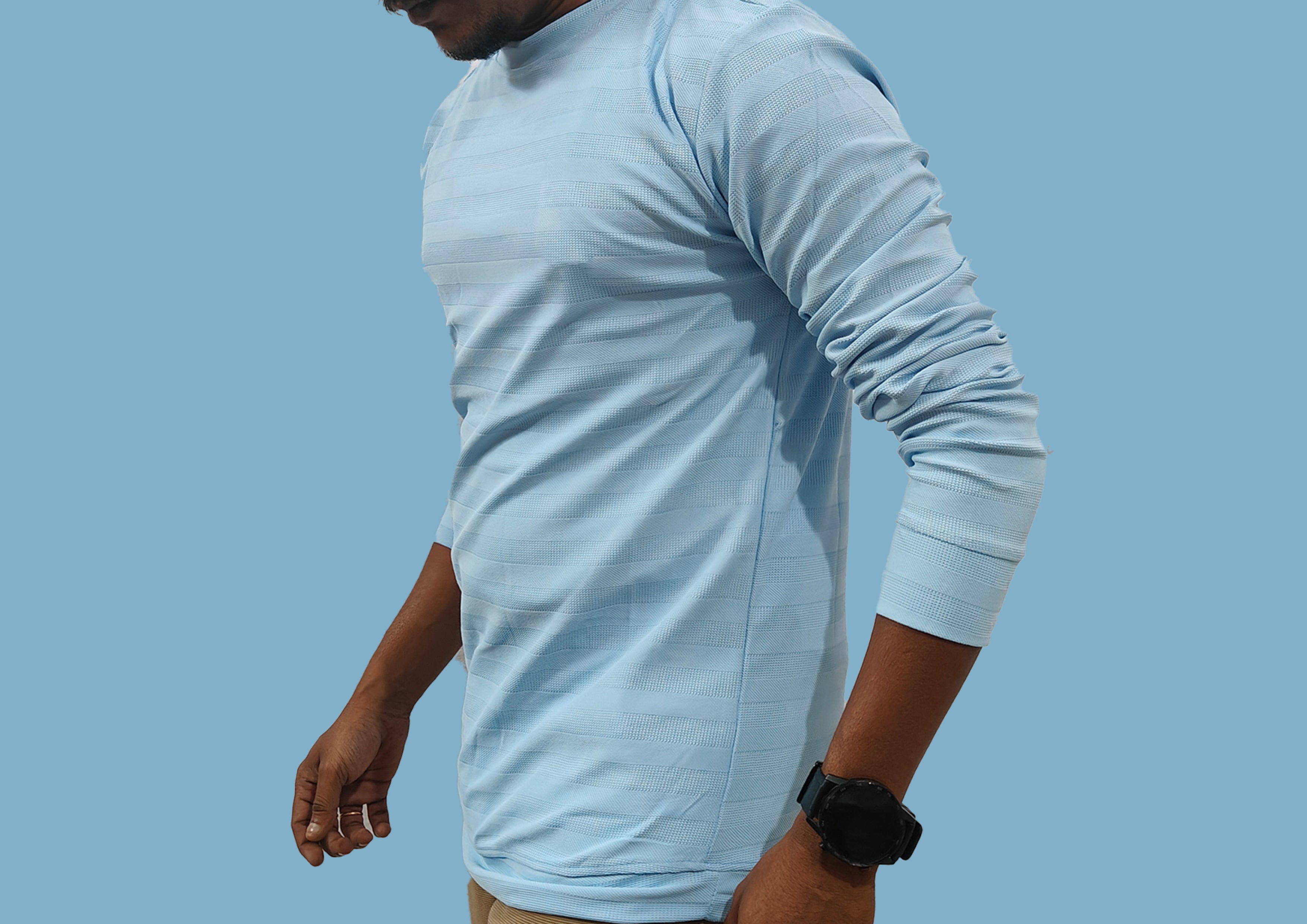 Person wearing a light blue long-sleeve shirt against a clear blue sky