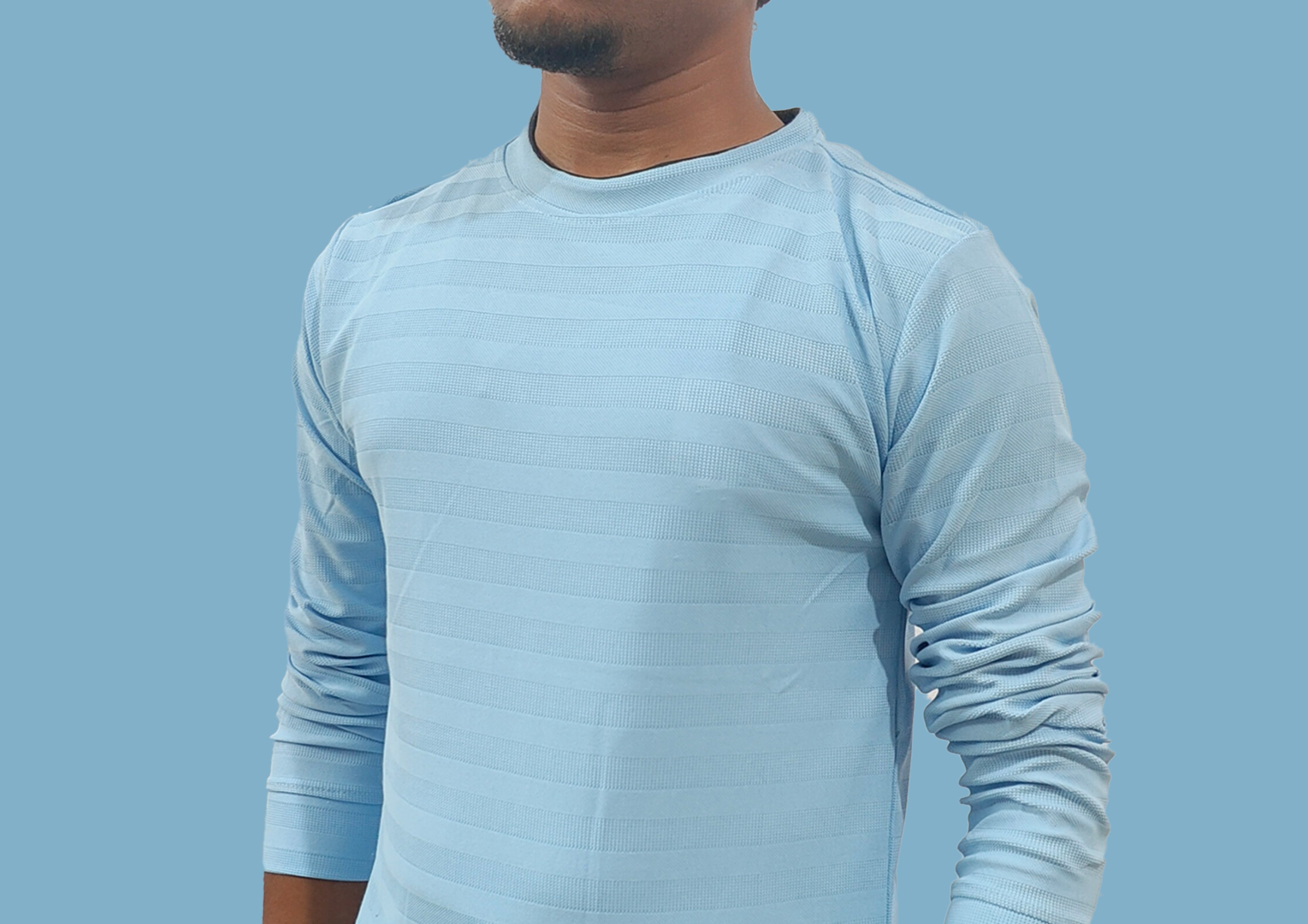 Person wearing a light blue long-sleeve shirt against a light blue background