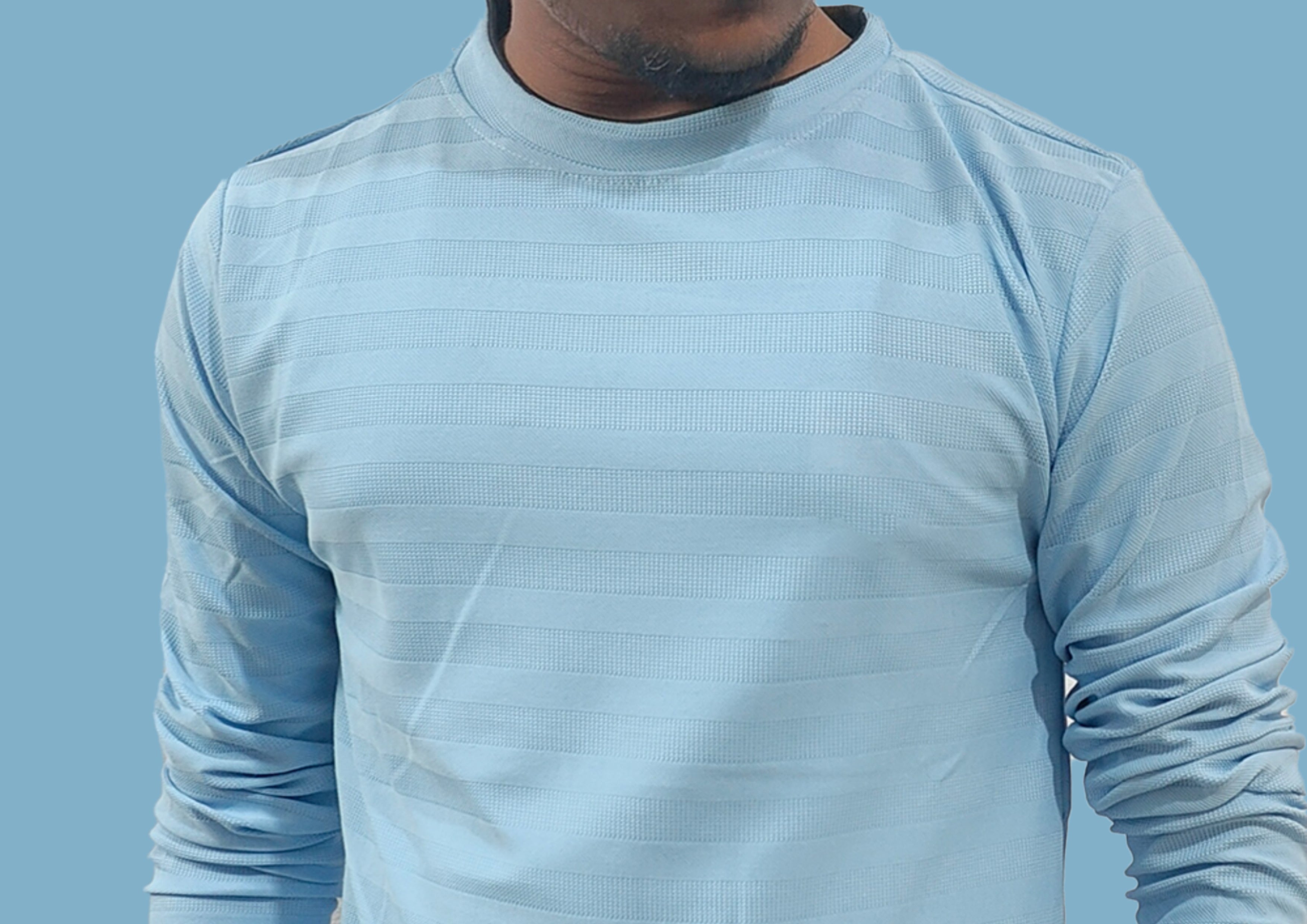 Person wearing a light blue long-sleeve shirt against a blue background