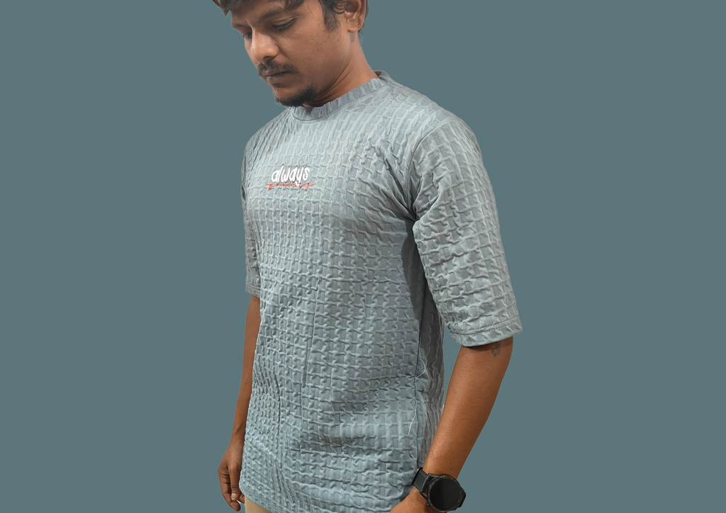 Man wearing a textured gray t-shirt with a logo on a plain background