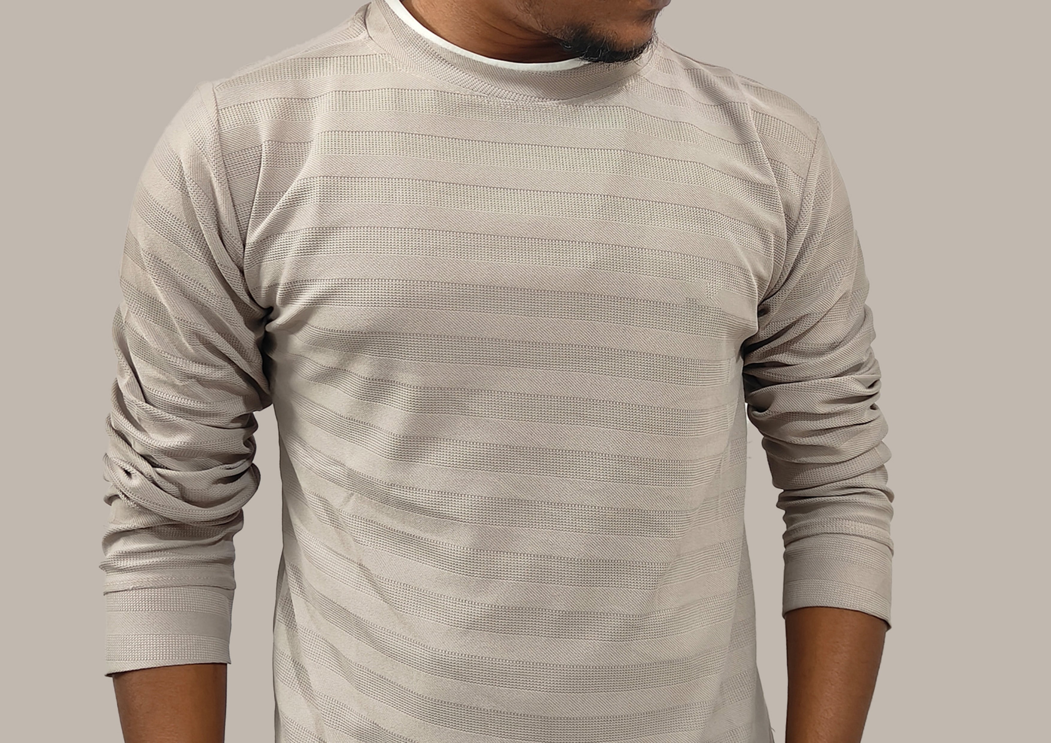 Man wearing a beige long-sleeve shirt against a plain background