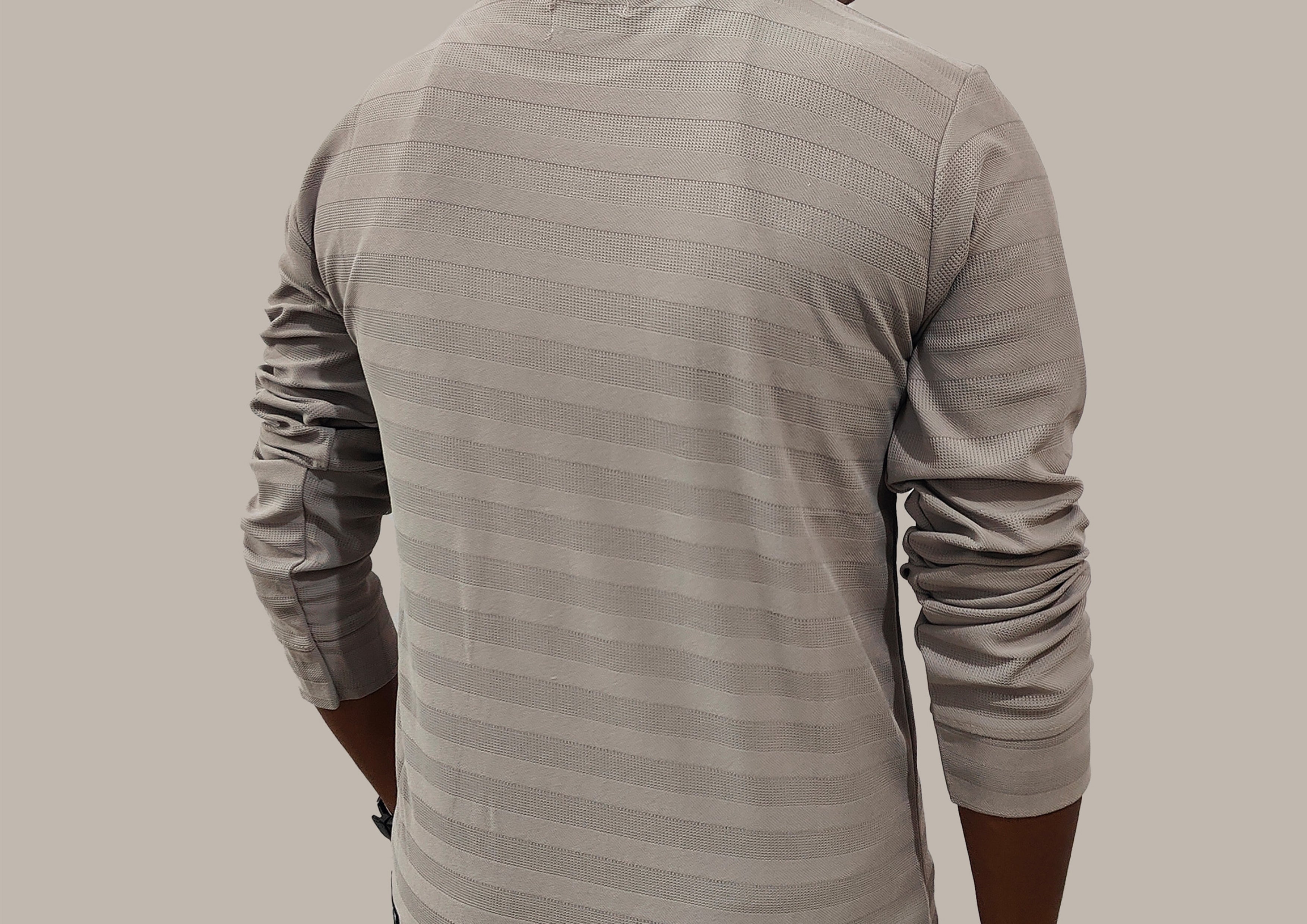 Person wearing a gray long-sleeve shirt with a subtle pattern on a plain background