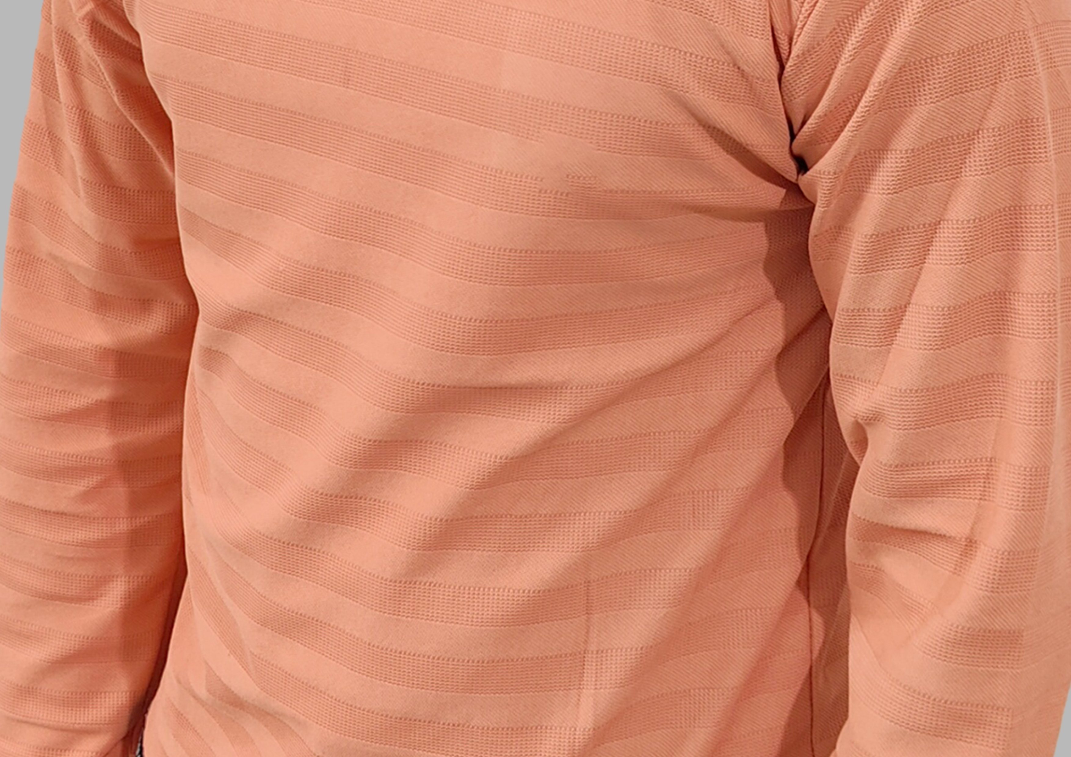 Close-up of a peach-colored long-sleeve shirt with textured fabric.