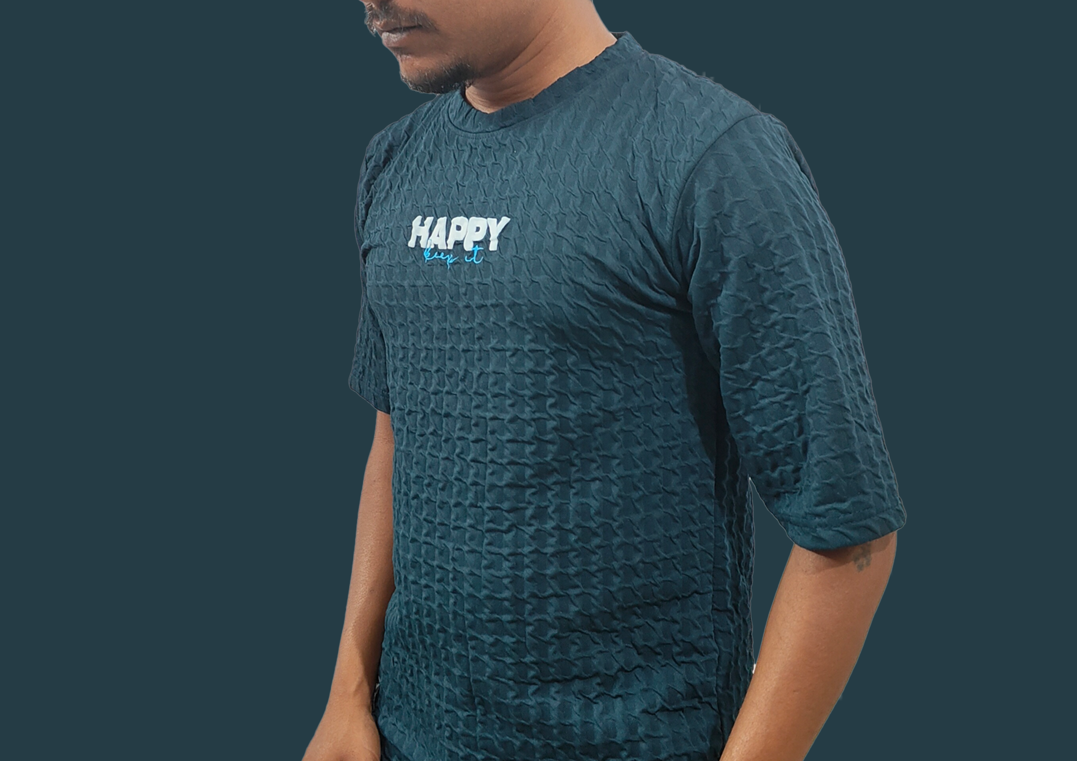 Person wearing a textured teal t-shirt with 'HAPPY' text on a dark background