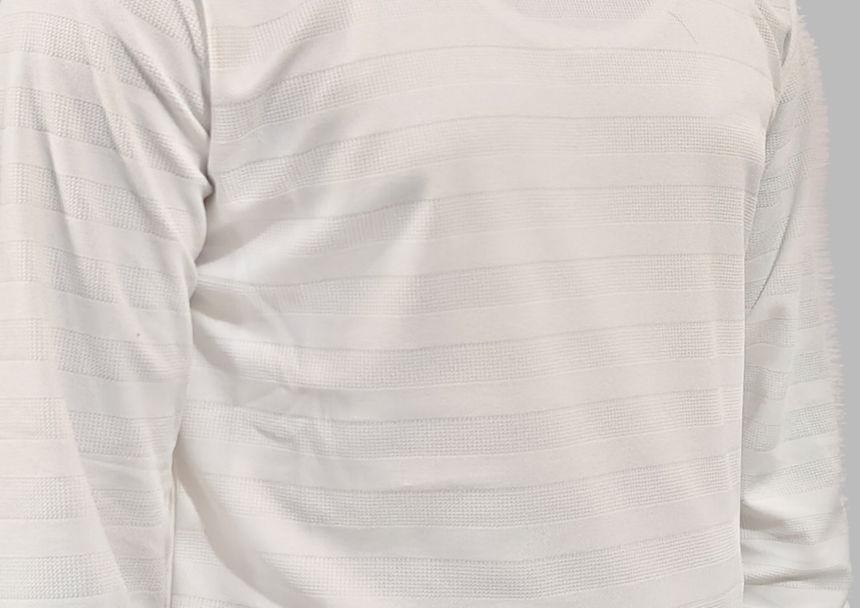 Close-up of a white long-sleeve shirt with subtle texture on a light gray background